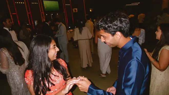 Two guests holding hands on the dance floor, eyes locked on each other mid-laugh