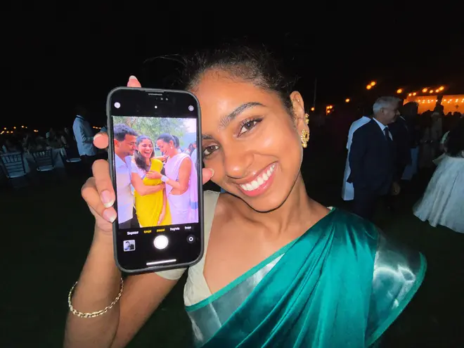 A wedding guest in a teal saree holding up the selfie she just took